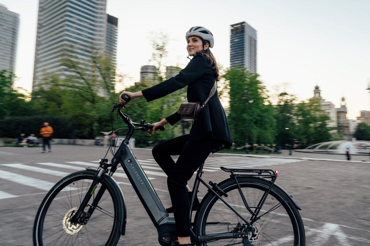 Moderne Mobilität: Elegante Geschäftsfrau auf dem Weg zur Arbeit mit einem City-E-Bike