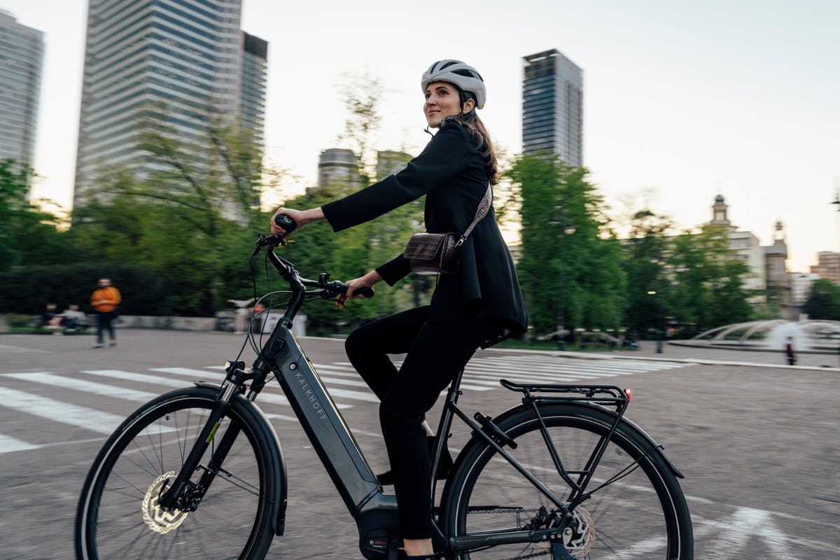 Moderne Mobilität: Elegante Geschäftsfrau auf dem Weg zur Arbeit mit einem City-E-Bike